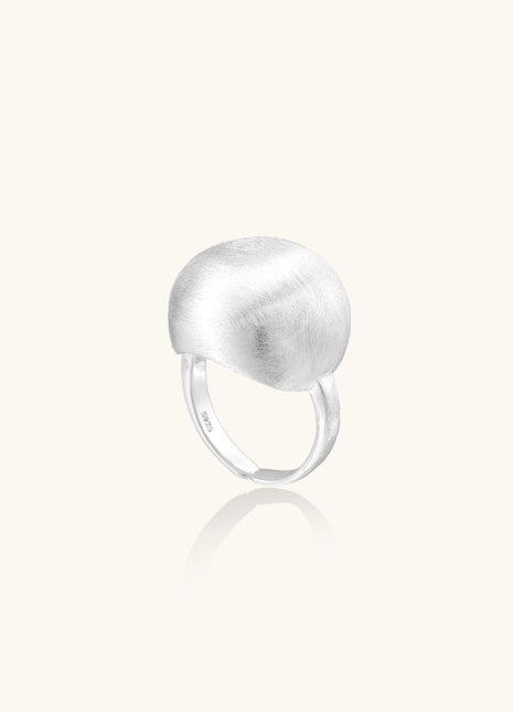 Minimalist sterling silver ring with large brushed disc top and adjustable band on white background.