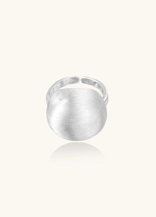 Minimalist sterling silver ring with large brushed disc top and adjustable band on white background.