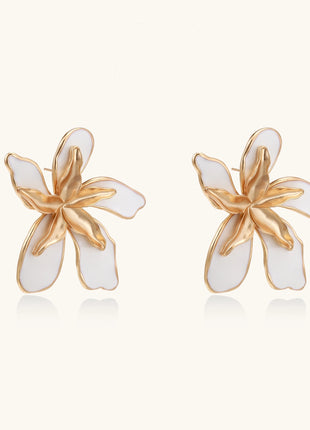 Large floral stud earrings with gold-plated brass petals and white enamel centers on neutral background