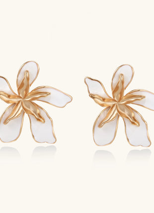 Large floral stud earrings with gold-plated brass petals and white enamel centers on neutral background