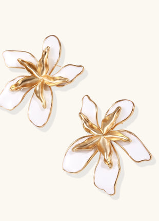 Large floral stud earrings with gold-plated brass petals and white enamel centers on neutral background