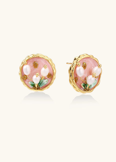 Round stud earrings with pink enamel background, white pearl tulips, green leaves, and twisted gold border on white background.