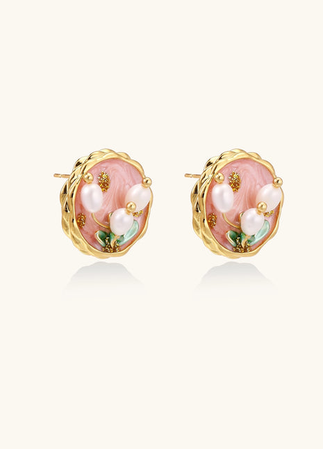 Round stud earrings with pink enamel background, white pearl tulips, green leaves, and twisted gold border on white background.