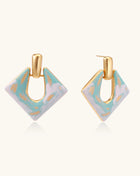 Diamond-shaped gold-plated earrings with pastel marble enamel in turquoise and lavender swirls on beige background