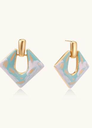 Diamond-shaped gold-plated earrings with pastel marble enamel in turquoise and lavender swirls on beige background