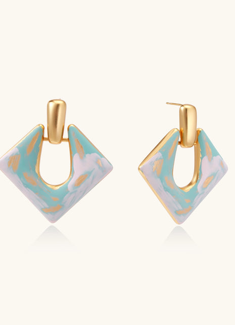 Diamond-shaped gold-plated earrings with pastel marble enamel in turquoise and lavender swirls on beige background