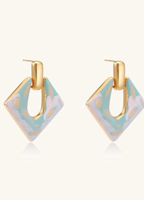 Diamond-shaped gold-plated earrings with pastel marble enamel in turquoise and lavender swirls on beige background