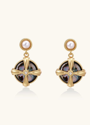 Gold-plated drop earrings with cross design framing iridescent abalone shell and pearl studs on neutral background.