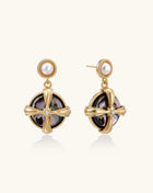 Gold-plated drop earrings with cross design framing iridescent abalone shell and pearl studs on neutral background.