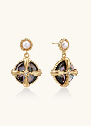 Gold-plated drop earrings with cross design framing iridescent abalone shell and pearl studs on neutral background.