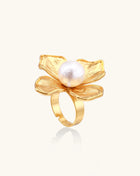 Gold-plated brass ring with dimensional 5-petal flower design and white cotton pearl center on neutral background.