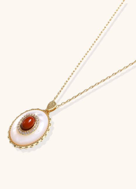 Oval gold-plated pendant featuring mother-of-pearl base with carnelian center stone and crystal accents on delicate chain