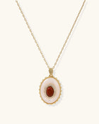 Oval gold-plated pendant featuring mother-of-pearl base with carnelian center stone and crystal accents on delicate chain