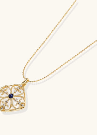 Gold-plated square pendant with ornate scrollwork featuring central blue lapis lazuli stone on ball chain