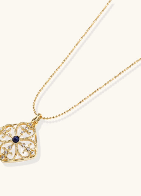 Gold-plated square pendant with ornate scrollwork featuring central blue lapis lazuli stone on ball chain
