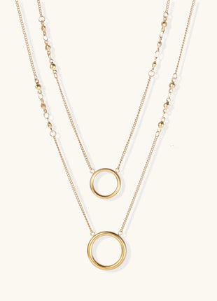 Gold-plated layered necklace set with two circular pendants featuring white centers on delicate chains.