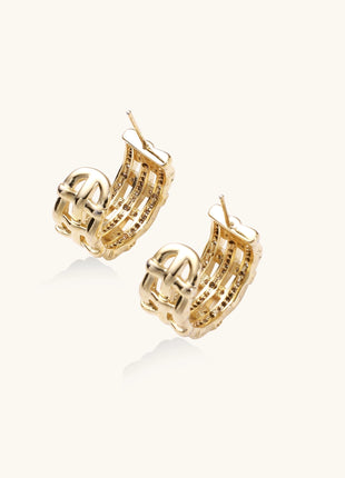 Close-up of geometric gold-plated hoop earrings with crystal pave in intricate lattice pattern on neutral background.