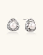 Close-up of triangular gold-plated stud earrings with central freshwater pearl surrounded by baguette crystals