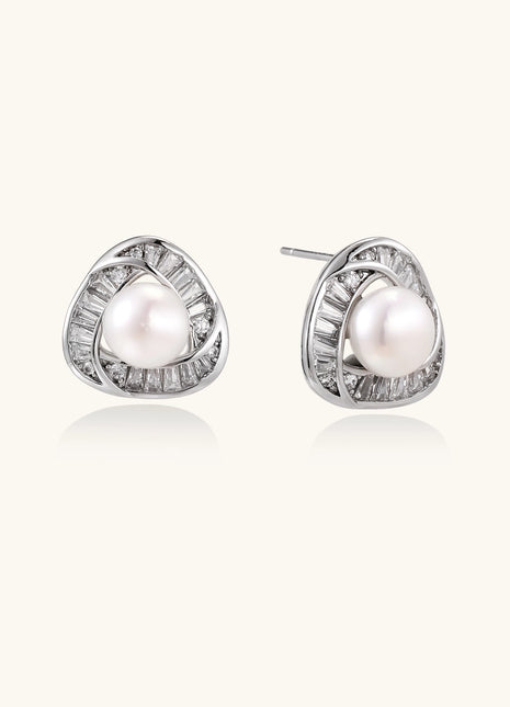 Close-up of triangular gold-plated stud earrings with central freshwater pearl surrounded by baguette crystals