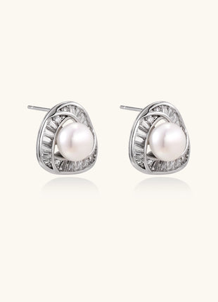 Close-up of triangular gold-plated stud earrings with central freshwater pearl surrounded by baguette crystals