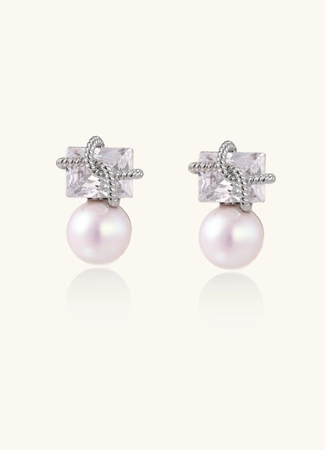 Gold-plated stud earrings with square crystal tops wrapped in twisted wire and freshwater pearl drops on white background