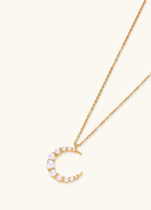 Delicate 18K gold plated necklace featuring crescent moon pendant with white shell pearl beads on neutral background.