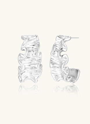 Textured gold-plated hoop earrings with flowing ripple design displayed on clean white background.