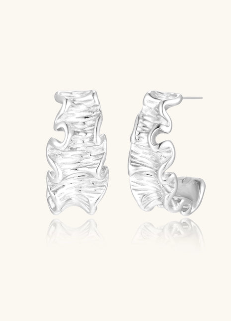 Textured gold-plated hoop earrings with flowing ripple design displayed on clean white background.