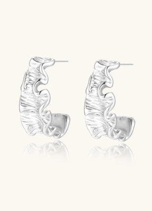 Textured gold-plated hoop earrings with flowing ripple design displayed on clean white background.