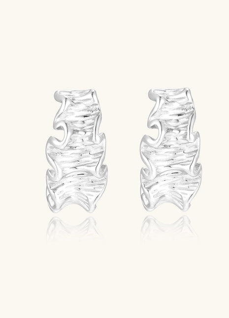 Textured gold-plated hoop earrings with flowing ripple design displayed on clean white background.