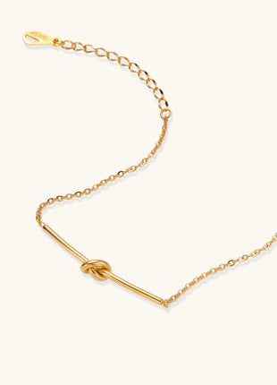 Delicate gold-plated chain bracelet with twisted knot bar detail and adjustable extender chain on white background.