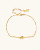 Delicate gold-plated chain bracelet with twisted knot bar detail and adjustable extender chain on white background.