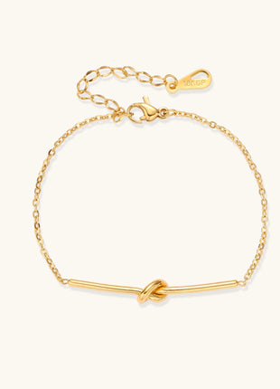 Delicate gold-plated chain bracelet with twisted knot bar detail and adjustable extender chain on white background.