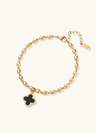 Dainty gold-plated beaded bracelet with oval links and four-leaf clover charm pendant on neutral background.