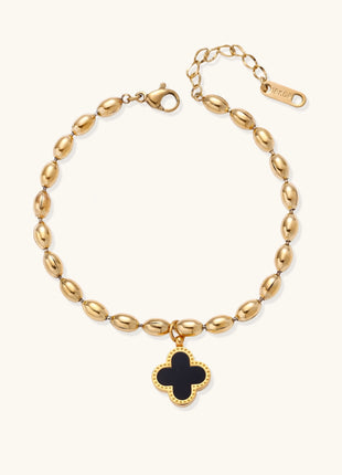 Dainty gold-plated beaded bracelet with oval links and four-leaf clover charm pendant on neutral background.