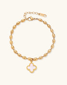Dainty gold-plated beaded bracelet with oval links and four-leaf clover charm pendant on neutral background.