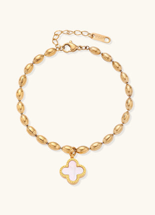 Dainty gold-plated beaded bracelet with oval links and four-leaf clover charm pendant on neutral background.