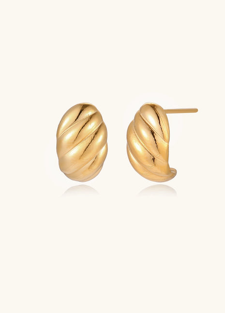 Pair of gold-plated twisted stud earrings with sculptural spiral design displaying elegant curved ridges on cream background.