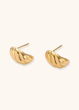 Pair of gold-plated twisted stud earrings with sculptural spiral design displaying elegant curved ridges on cream background.