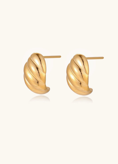Pair of gold-plated twisted stud earrings with sculptural spiral design displaying elegant curved ridges on cream background.