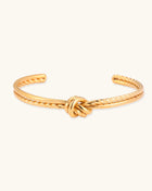 18K gold-plated twisted rope cuff bracelet with decorative knot detail on white background, showing adjustable open design.