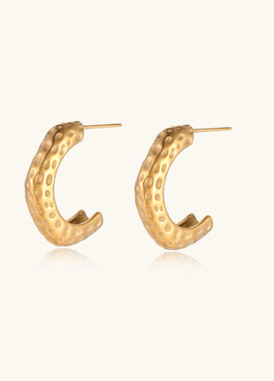 Textured gold-plated hoop earrings with dimpled surface pattern and post backs on neutral background.