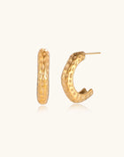 Textured gold-plated hoop earrings with dimpled surface pattern and post backs on neutral background.