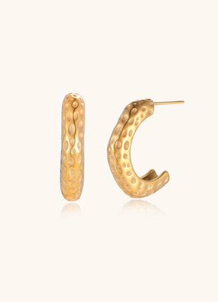 Textured gold-plated hoop earrings with dimpled surface pattern and post backs on neutral background.