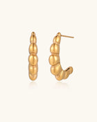 Gold-plated stainless steel hoop earrings with segmented bubble design and post closure on white background